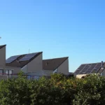Modern houses with sloped roofs and solar panels, surrounded by greenery, showcasing sustainable energy solutions for homeowners in the Netherlands.