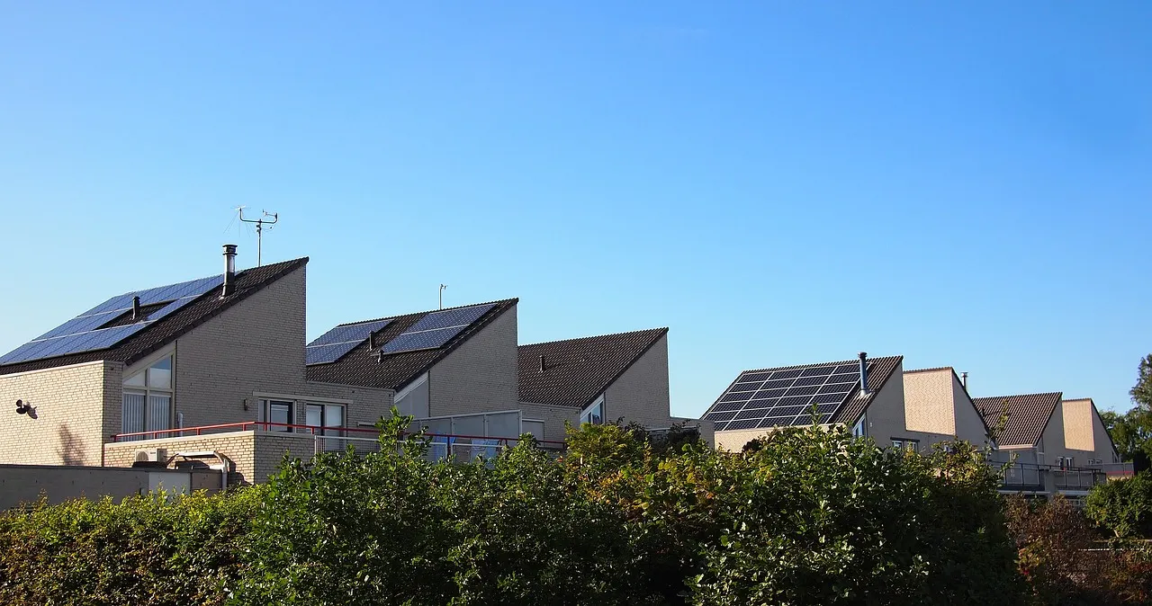 Modern houses with sloped roofs and solar panels, surrounded by greenery, showcasing sustainable energy solutions for homeowners in the Netherlands.